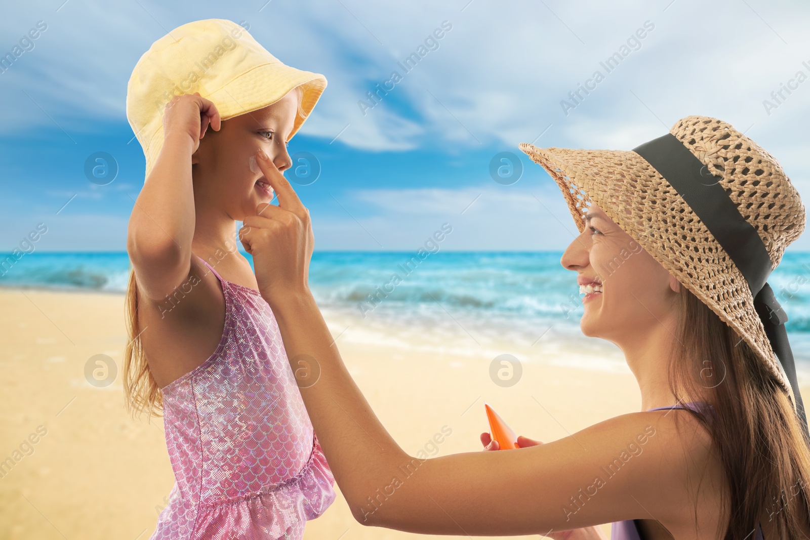 Image of Mother applying sunscreen onto her daughter's face at beach. Sun protection while outdoor recreation in summer
