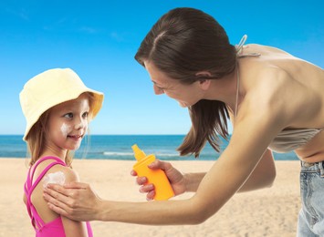 Image of Mother applying sunscreen onto her daughter's skin at beach. Sun protection while outdoor recreation in summer