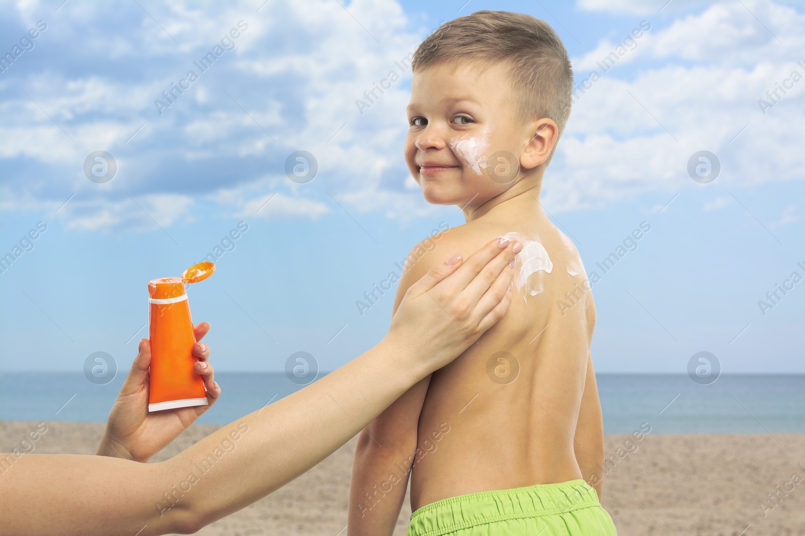 Mother applying sunscreen onto her son's skin at beach, closeup. Sun protection while outdoor recreation in summer Image of Mother applying sunscreen onto her son's skin at beach, closeup. Sun protection while outdoor recreation in summer