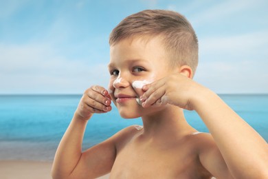 Image of Little boy applying sunscreen on his face at beach. Sun protection while outdoor recreation in summer