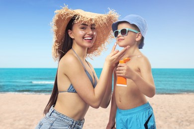 Image of Mother applying sunscreen onto her son's skin at beach. Sun protection while outdoor recreation in summer