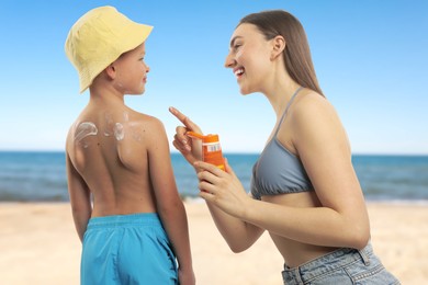 Image of Mother applying sunscreen onto her son's skin at beach. Sun protection while outdoor recreation in summer