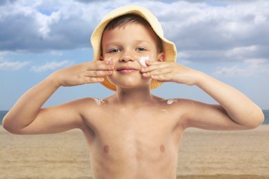 Image of Little boy applying sunscreen on his face at beach. Sun protection while outdoor recreation in summer