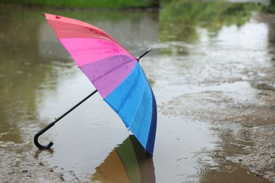 Photo of Colorful umbrella on wet asphalt under heavy rain. Space for text