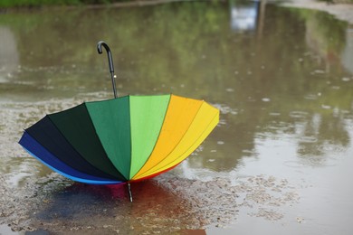 Photo of Colorful umbrella on wet asphalt under heavy rain. Space for text