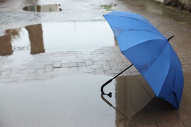 Photo of Blue umbrella on wet asphalt outdoors, space for text
