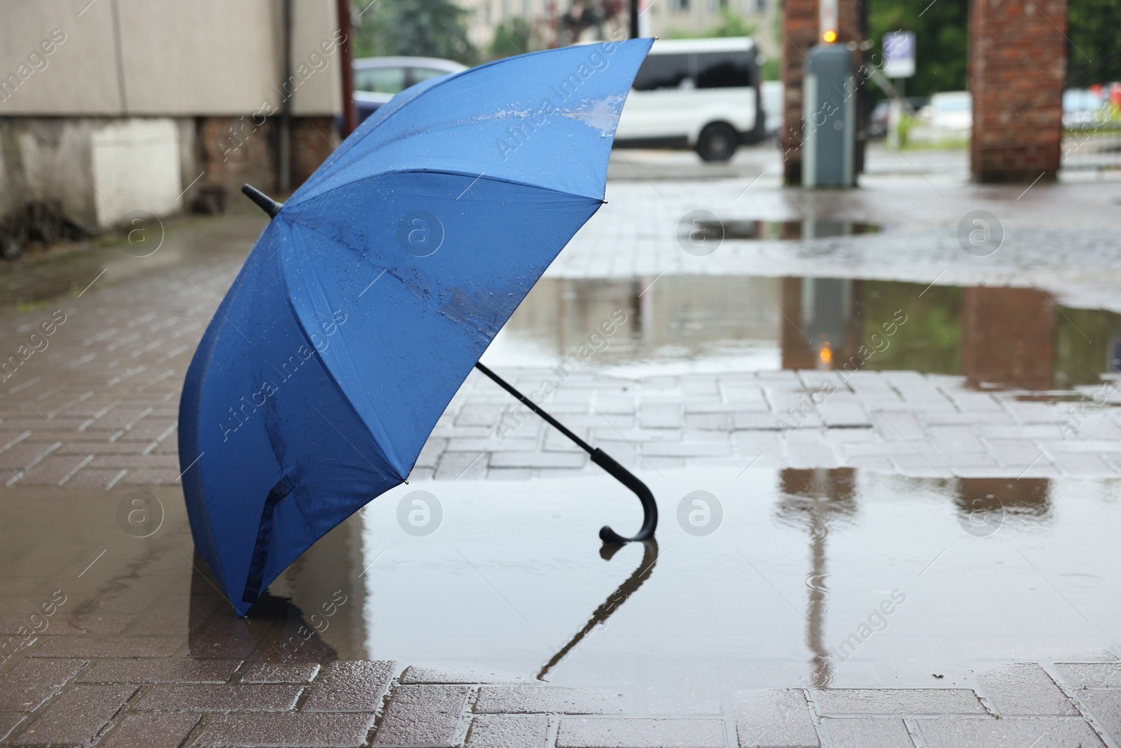 Blue umbrella on wet asphalt outdoors, space for text Photo of Blue umbrella on wet asphalt outdoors, space for text