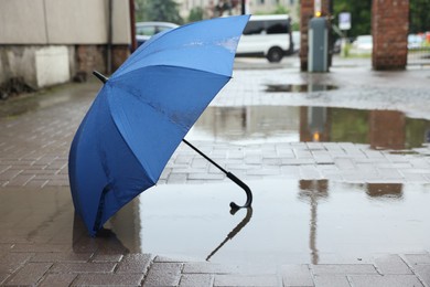 Photo of Blue umbrella on wet asphalt outdoors, space for text