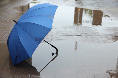 Photo of Blue umbrella on wet asphalt outdoors, space for text