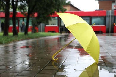 Photo of Yellow umbrella on wet asphalt outdoors, space for text