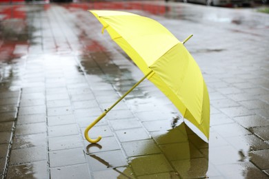 Photo of Yellow umbrella on wet asphalt outdoors, space for text