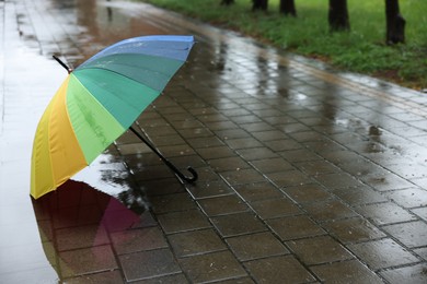 Photo of Colorful umbrella on wet asphalt outdoors, space for text