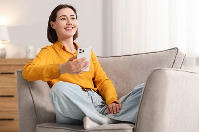 Photo of Woman using modern smartphone in armchair at home. Space for text