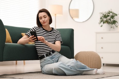Photo of Woman using modern smartphone on floor at home. Space for text