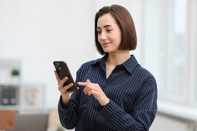 Photo of Beautiful woman using her smartphone in office