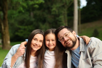 Photo of Family portrait of smiling parents and daughter outdoors