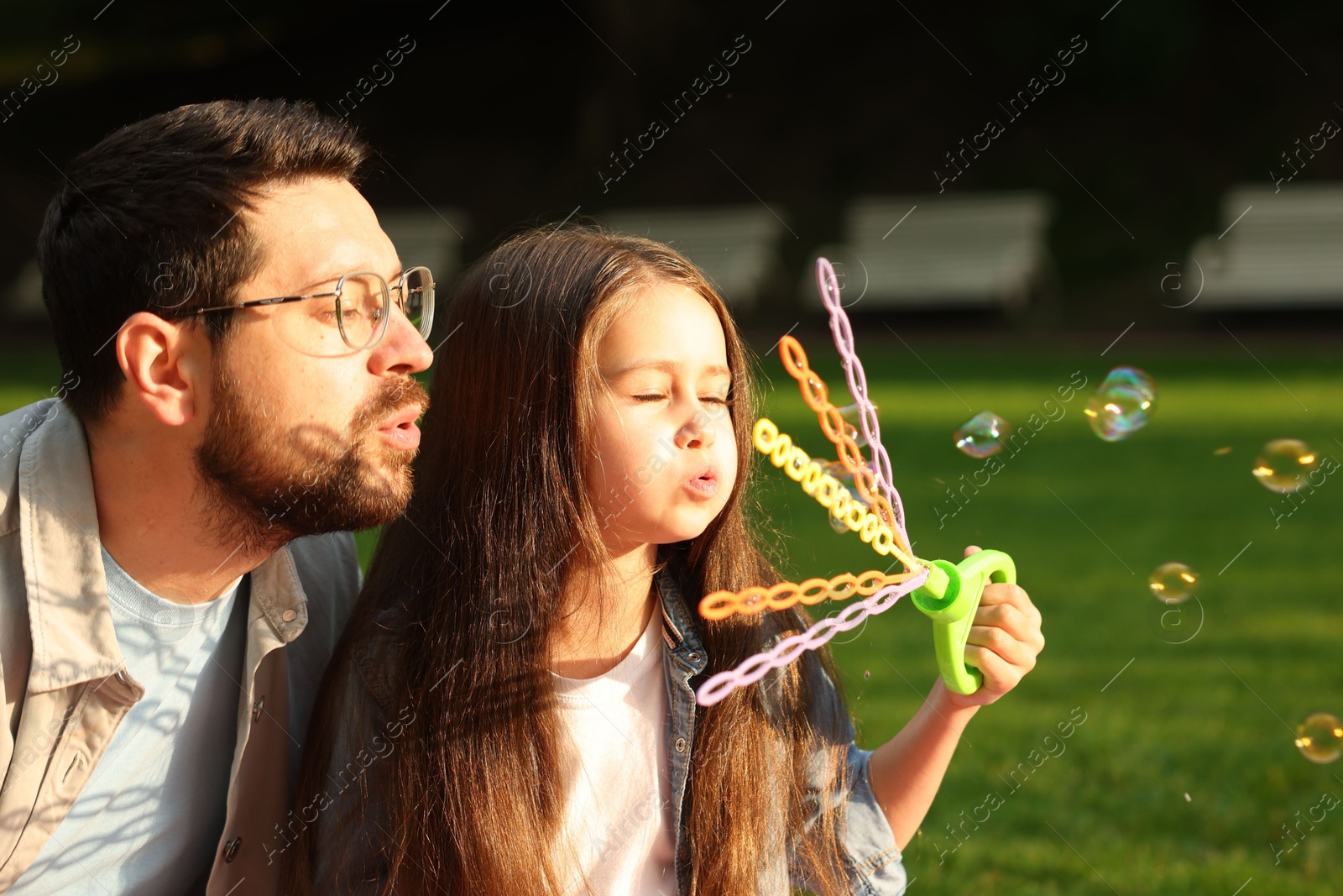 Photo of Family getaway. Father and daughter blowing soap bubbles outdoors