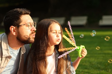 Photo of Family getaway. Father and daughter blowing soap bubbles outdoors