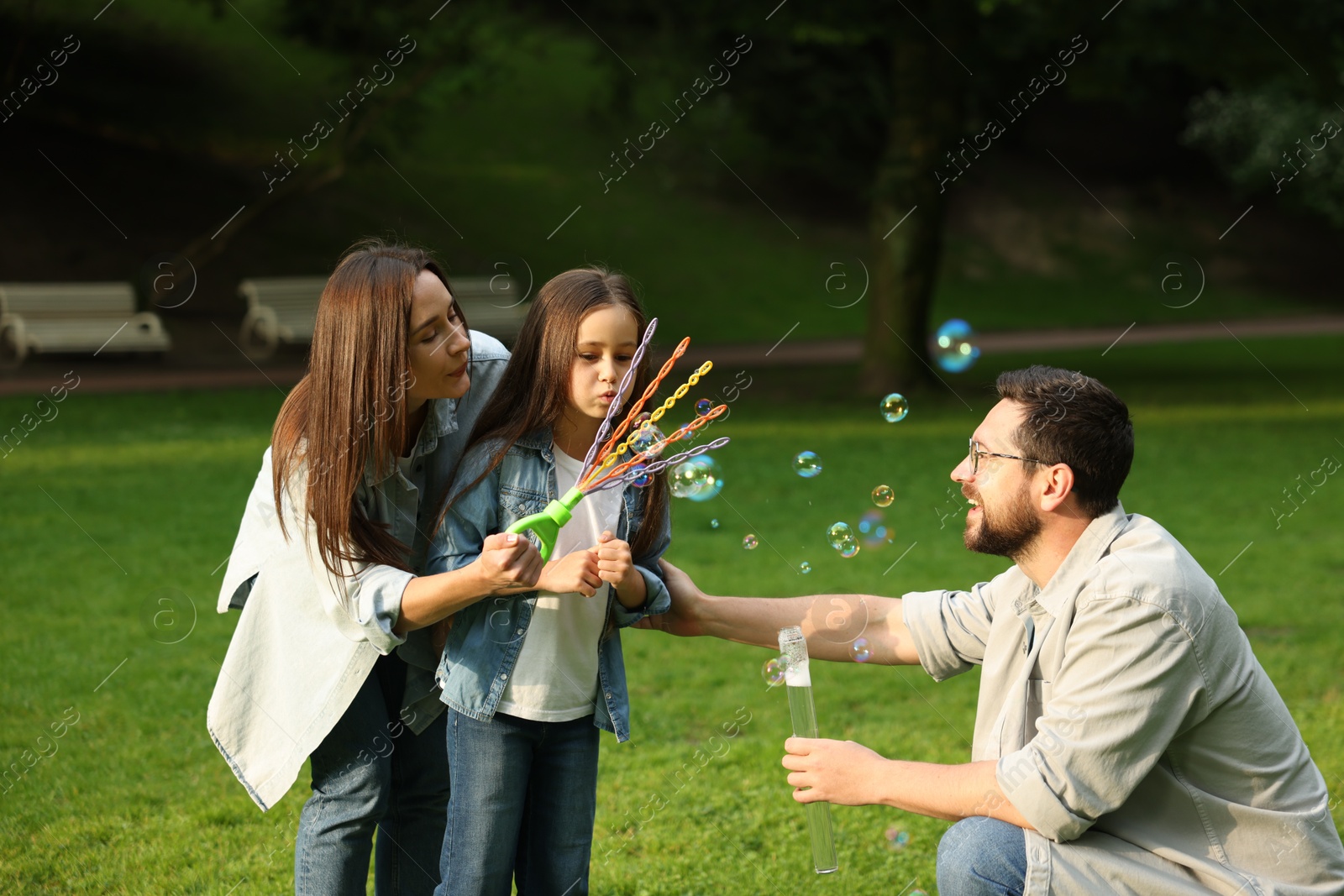 Happy family blowing soap bubbles in park Photo of Happy family blowing soap bubbles in park
