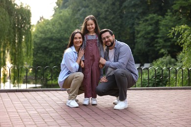 Photo of Family weekend. Smiling parents and daughter posing in park