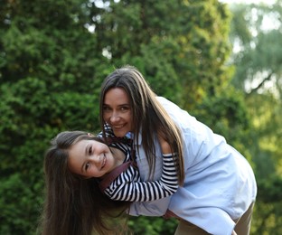 Photo of Family portrait of smiling mother and daughter in park