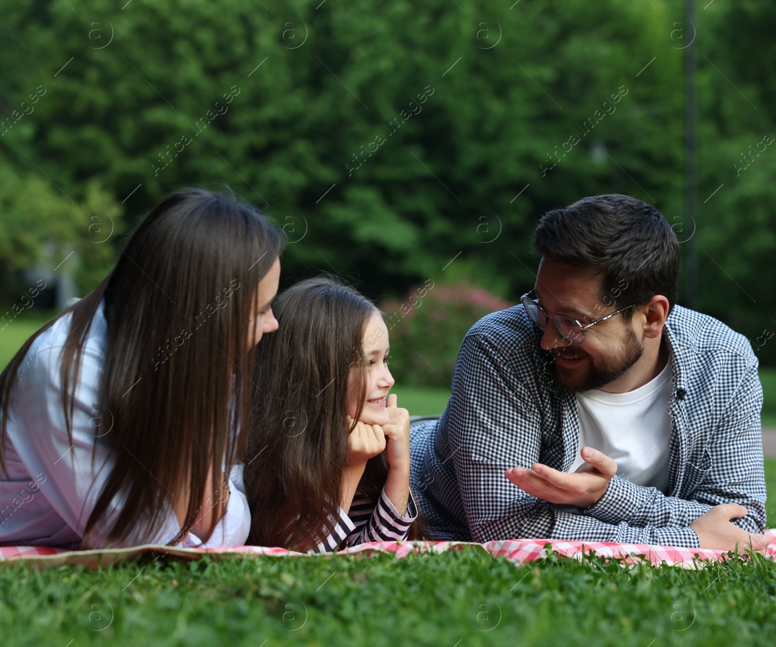 Happy family spending time together on checkered picnic blanket outdoors Photo of Happy family spending time together on checkered picnic blanket outdoors
