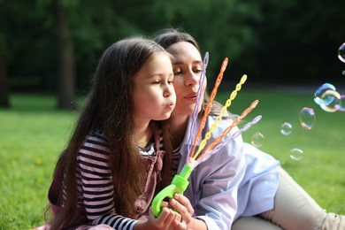 Photo of Family holiday getaway. Mother and daughter blowing soap bubbles outdoors