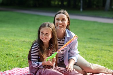 Photo of Family holiday getaway. Happy mother and daughter spending time together on checkered picnic blanket outdoors