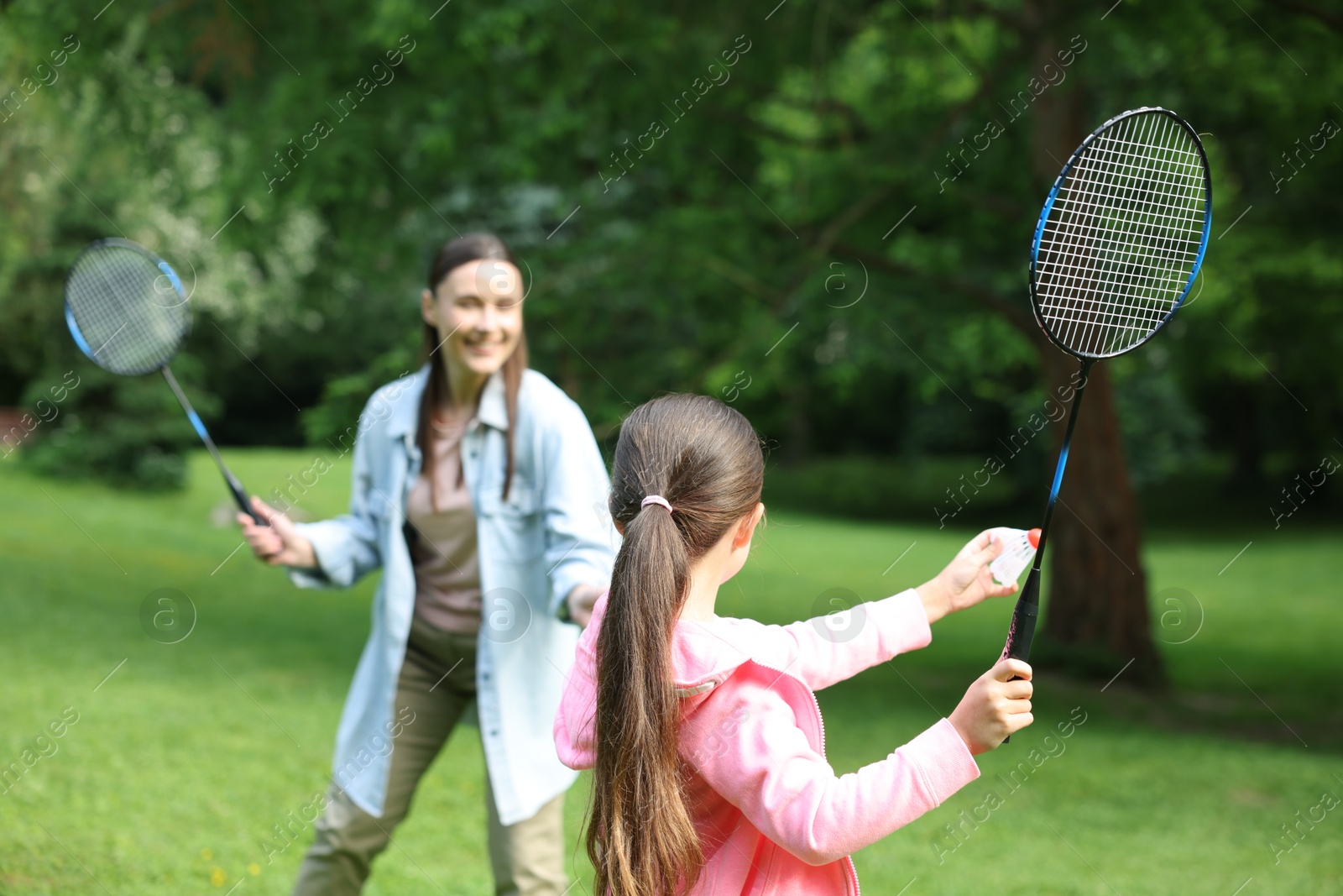 Family getaway. Daughter playing badminton with her mother outdoors, selective focus Photo of Family getaway. Daughter playing badminton with her mother outdoors, selective focus