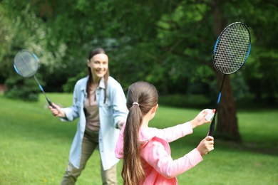Photo of Family getaway. Daughter playing badminton with her mother outdoors, selective focus