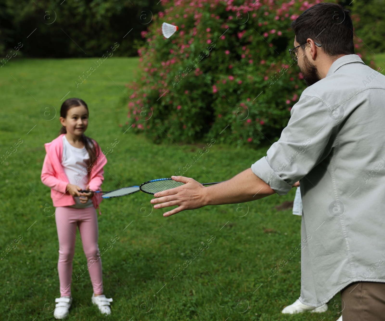 Family getaway. Father playing badminton with his daughter outdoors, selective focus Photo of Family getaway. Father playing badminton with his daughter outdoors, selective focus