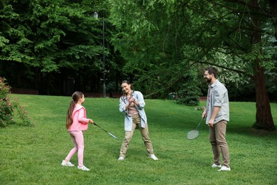 Photo of Happy family playing badminton on green grass in park