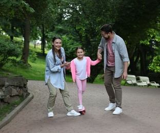 Photo of Happy family having fun with penny board in park