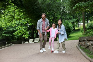 Photo of Happy family having fun with penny board in park