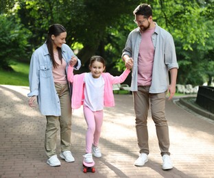 Photo of Happy family having fun with penny board in park