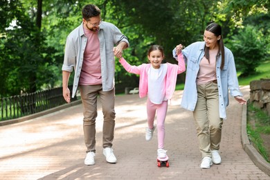 Photo of Happy family having fun with penny board in park