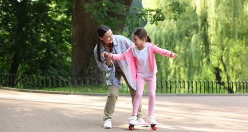 Photo of Family getaway. Happy mother and daughter having fun with penny board in park