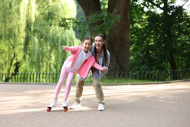 Photo of Family getaway. Happy mother and daughter having fun with penny board in park