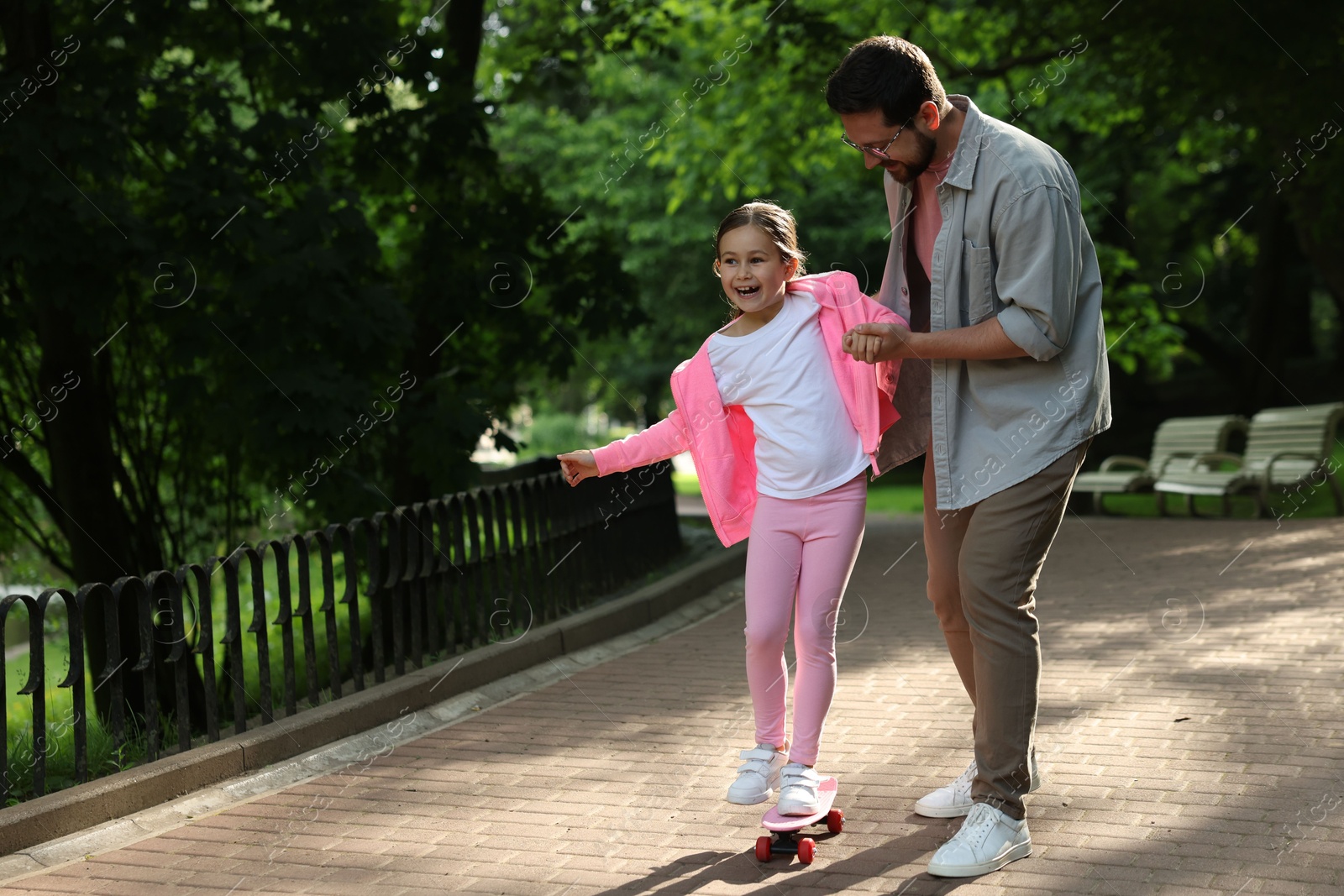 Family getaway. Happy father and daughter having fun with penny board in park. Space for text Photo of Family getaway. Happy father and daughter having fun with penny board in park. Space for text