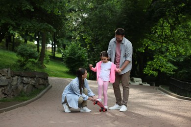 Photo of Happy family having fun with penny board in park