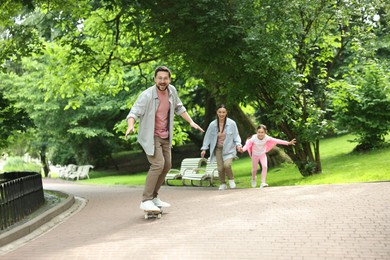Photo of Happy family having fun with skateboard in park