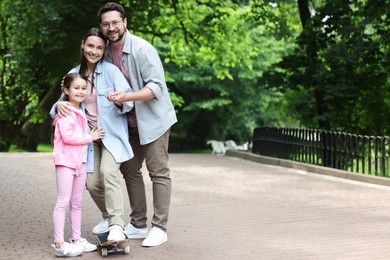 Photo of Happy family having fun with skateboard in park. Space for text