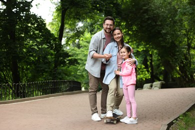 Photo of Happy family having fun with skateboard in park. Space for text