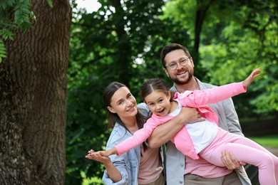 Photo of Family portrait of smiling parents and daughter outdoors