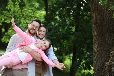 Photo of Family portrait of smiling parents and daughter outdoors