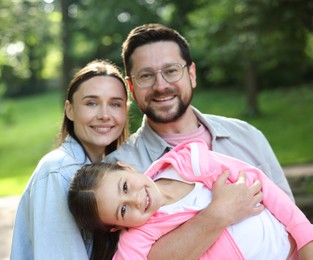 Photo of Family portrait of smiling parents and daughter outdoors