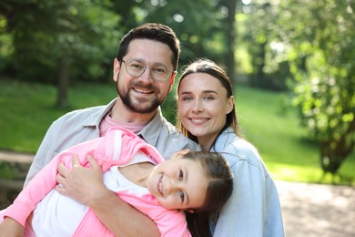 Photo of Family portrait of smiling parents and daughter outdoors