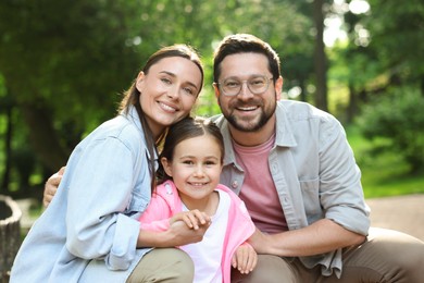 Photo of Family portrait of smiling parents and daughter outdoors