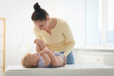Photo of Mother with her cute baby on changing table at home