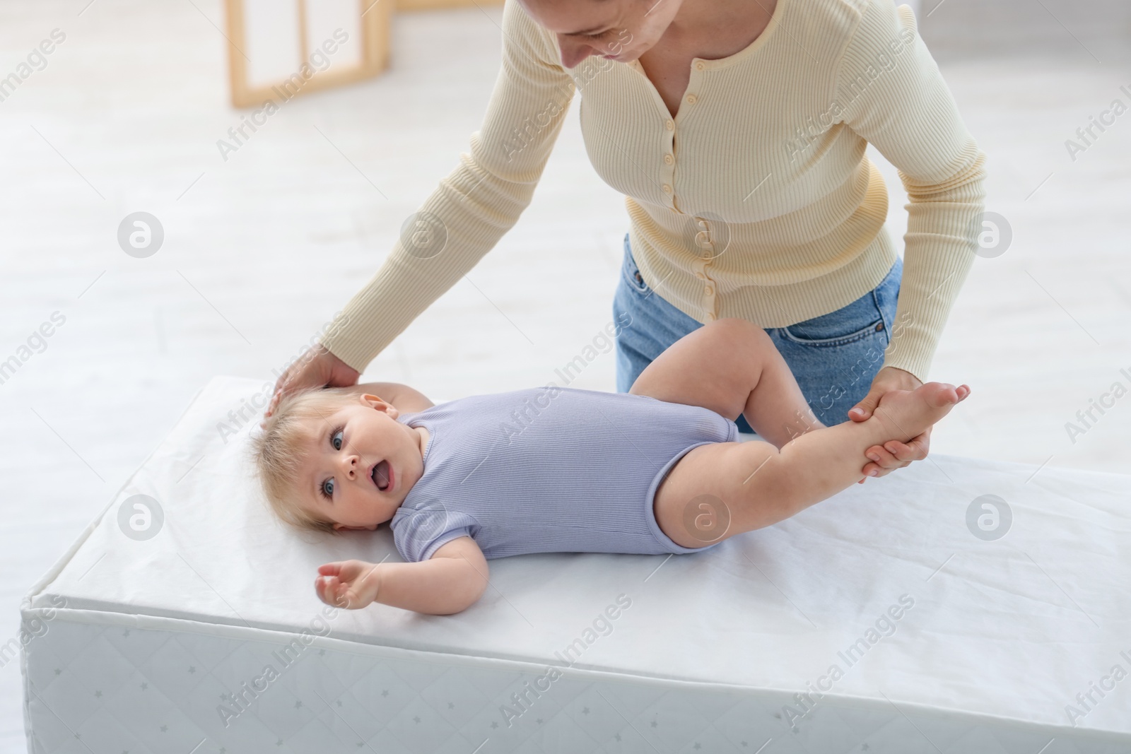 Mother with her cute baby on changing table at home Photo of Mother with her cute baby on changing table at home
